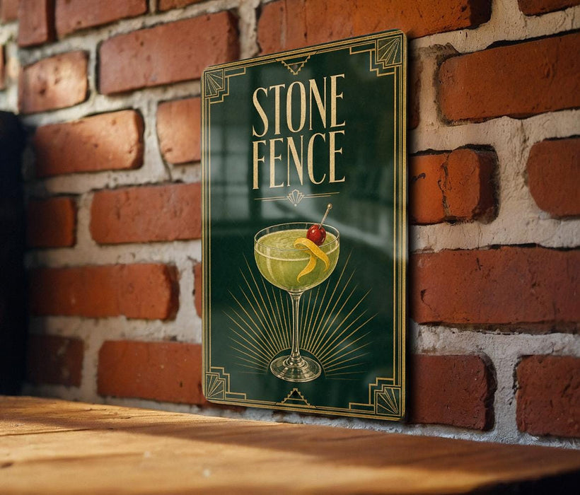 A framed poster of a cocktail with a cherry on top, hanging on a brick wall.