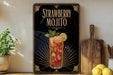 A framed advertisement for a strawberry mojito cocktail, featuring a glass of the drink with a lemon slice and mint leaves.