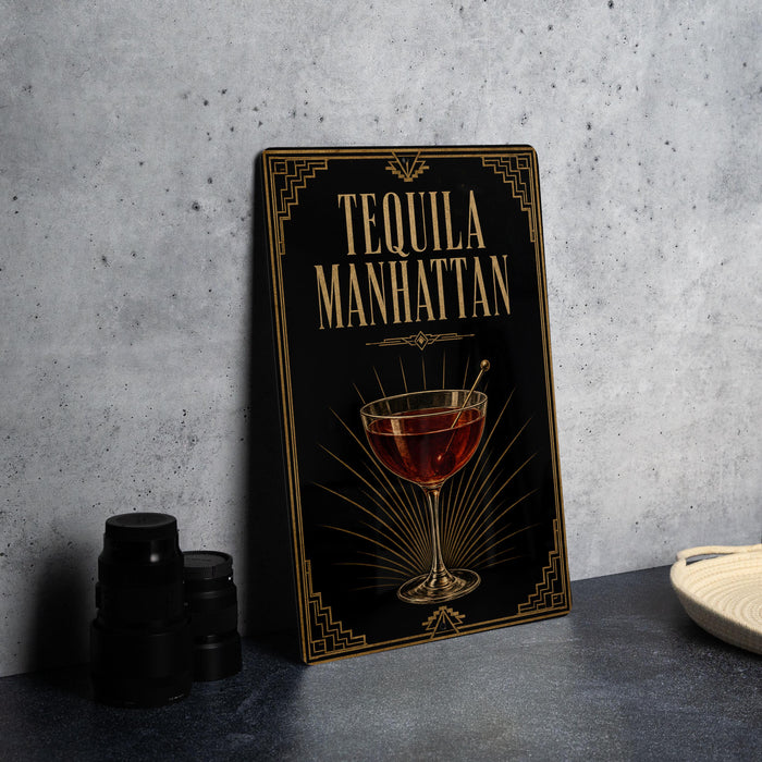 A framed poster of a tequila Manhattan cocktail is displayed on a wall, accompanied by a stack of black camera lenses and a white dish.