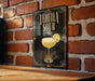 A sign with the text "TEQUILA SOUR" and an illustration of a tequila sour cocktail on a brick wall.