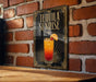A sign for "Tequila Sunrise" is displayed on a brick wall, featuring an illustration of a colorful tequila sunrise cocktail.