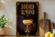 A sign for "Toasted Almond" cocktail, featuring an illustration of a cocktail glass with a toasted almond garnish.
