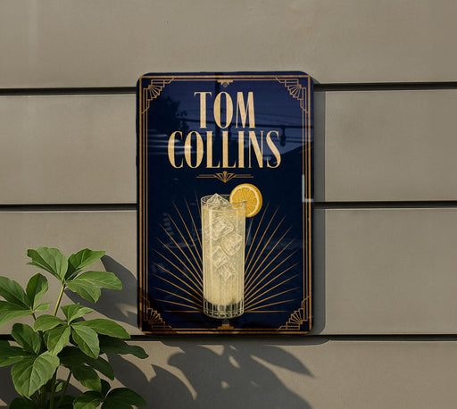 A sign for a cocktail named "Tom Collins" is displayed on a wall, featuring an illustration of a cocktail glass with a lemon slice.