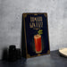 A decorative sign for a cocktail called "Tomato Gin Fizz" is displayed on a table, featuring an illustration of a cocktail glass with a garnish.