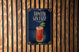 A sign for a cocktail called "Tomato Gin Fizz" is displayed on a wooden wall.