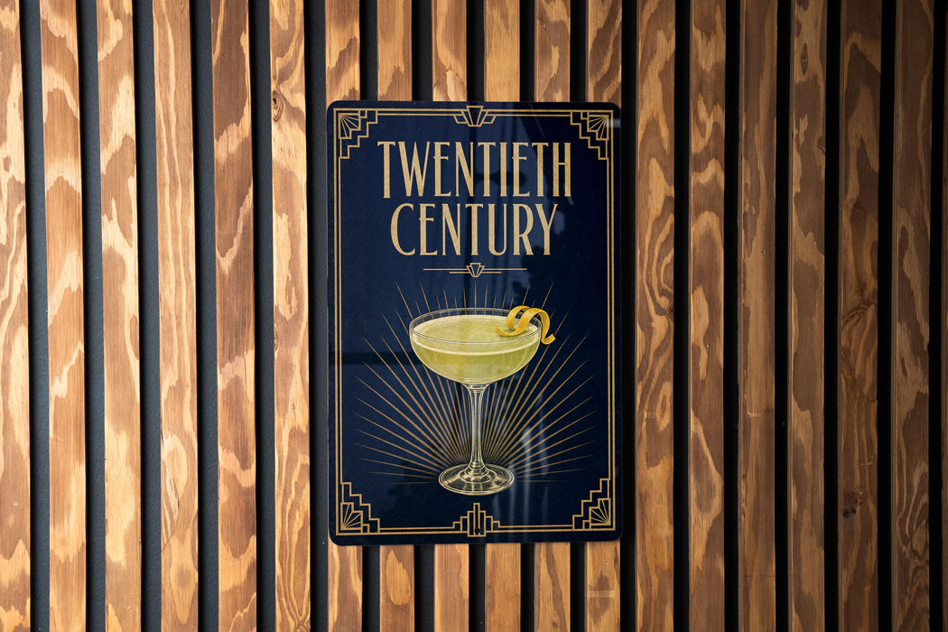 A sign for a "Twentieth Century" cocktail, featuring an illustration of a cocktail glass with a lemon twist on a dark background.