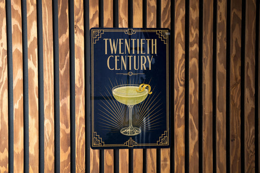 A sign for a "Twentieth Century" cocktail, featuring an illustration of a cocktail glass with a lemon twist on a dark background.