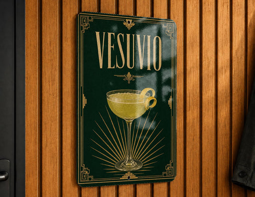 A framed poster with the word "VESUVO" prominently displayed, featuring an illustration of a cocktail glass with a lemon twist.