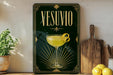 a framed poster of a cocktail glass with a lemon twist, placed on a shelf next to a wooden cutting board and a potted plant.