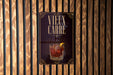 a poster with a glass of amber-colored liquid and a lemon slice, displayed on a wooden wall.