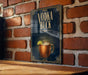 A sign with the text "VODKA BUCK" and an illustration of a copper mug with a lime wedge, mounted on a brick wall.