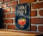 A sign for a vodka punch is displayed on a brick wall.