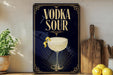 a poster with a stylized illustration of a cocktail glass filled with a yellow liquid, accompanied by the text "VODKA SOUR" in a decorative font.