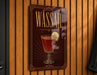A sign for "Wassail" cocktail is displayed on a wooden wall.