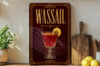 A framed advertisement for a drink called "Wassail" featuring a glass of the drink with a lemon slice.