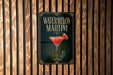 A sign for a watermelon martini is displayed on a wooden wall.