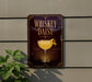 A sign for a whiskey daisy cocktail is displayed on a wall, featuring a glass of the drink with a lemon twist.