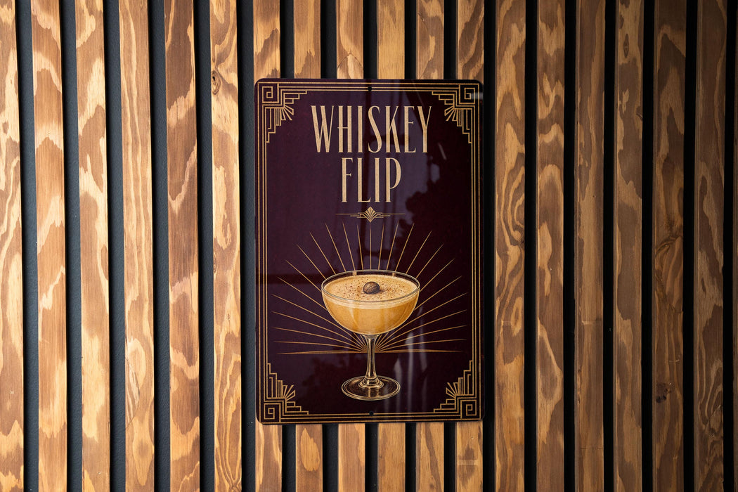 A sign for a whiskey flip cocktail is displayed on a wooden wall.