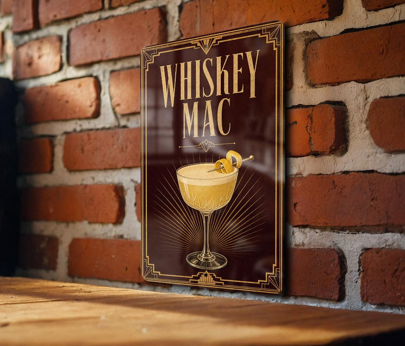 A poster with the text "WHISKEY MAC" and an illustration of a cocktail glass with a lemon twist, displayed on a brick wall.