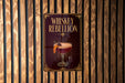 A poster with the title "Whiskey Rebellion" displayed on a wooden wall.