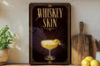A framed poster with the text "WHISKEY SKIN" and an illustration of a cocktail on a wooden shelf.