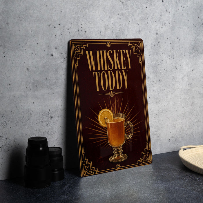 A dark wooden sign with a decorative border and the text "WHISKEY TODDY" is displayed on a gray countertop.