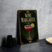 A framed image of a wine margarita on a wall, with a stack of black cups and a white dish nearby.