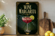 A wine margarita sign is displayed on a wooden shelf, accompanied by a potted plant, a wooden cutting board, and some lemons.