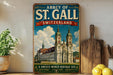 A vintage-style metal sign displaying the name "Abbey of St. Gall Switzerland" and a picture of St. Gall Cathedral, with additional text indicating it is a UNESCO World Heritage Site.