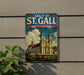 A vintage metal sign displaying the Abbey of St. Gall, Switzerland, with a colorful illustration of the historic building.