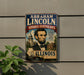 a vintage-style metal sign with an illustration of Abraham Lincoln, the 16th President of the United States, and the text "Abraham Lincoln National Heritage Area Illinois".