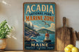 A vintage-style metal sign for Acadia National Park's Marine Zone, featuring a scenic image of a lighthouse and a rocky coastline.