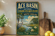 A vintage-style sign for the Ace Basin National Estuarine Research Reserve in South Carolina, featuring a seagull and a tropical landscape.
