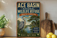 A vintage-style sign for Ace Basin National Wildlife Refuge in South Carolina, featuring an illustration of a heron in a lush, tropical landscape.