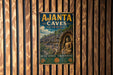 A vintage metal sign with the text "Ajanta Caves India" and an illustration of a temple or cave, mounted on a wooden wall.