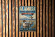 A vintage-style metal sign for the Alamo National Wildlife Refuge in Colorado, featuring an illustration of ducks swimming in a lake.