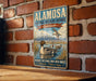 A vintage-style metal sign for the Almosa National Wildlife Refuge in Colorado, featuring a duck and a mountain landscape.
