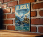 A vintage metal sign for the Alaska Maritime National Wildlife Refuge, featuring an illustration of a seal, a whale, and mountains.