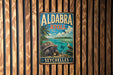 A vintage metal sign with the text "ALDABRA ATOLL SEYCHELLES" is displayed on a wooden wall.