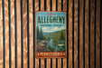A vintage-style metal sign for Pennsylvania's Allegheny National Forest, featuring a scenic mountain landscape with pine trees and a river.