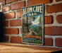A vintage-style metal sign for the Alum Cave Trail in Tennessee, featuring a scenic mountain landscape with a winding trail.