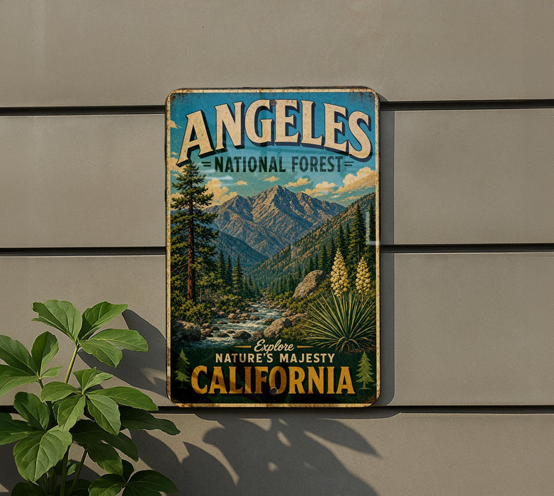 A vintage metal sign for the Angeles National Forest in California, featuring a scenic mountain landscape with pine trees, a river, and a waterfall.