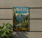 A vintage metal sign for the Angeles National Forest in California, featuring a scenic mountain landscape with pine trees, a river, and a waterfall.