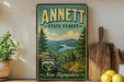 A vintage-style metal sign for the Annett State Forest in New Hampshire, featuring a scenic mountain landscape and pine trees.