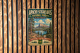 A vintage metal sign for Apache-SITGREAVES NATIONAL FORESTS ARIZONA, featuring a scenic landscape with mountains, trees, and a lake.