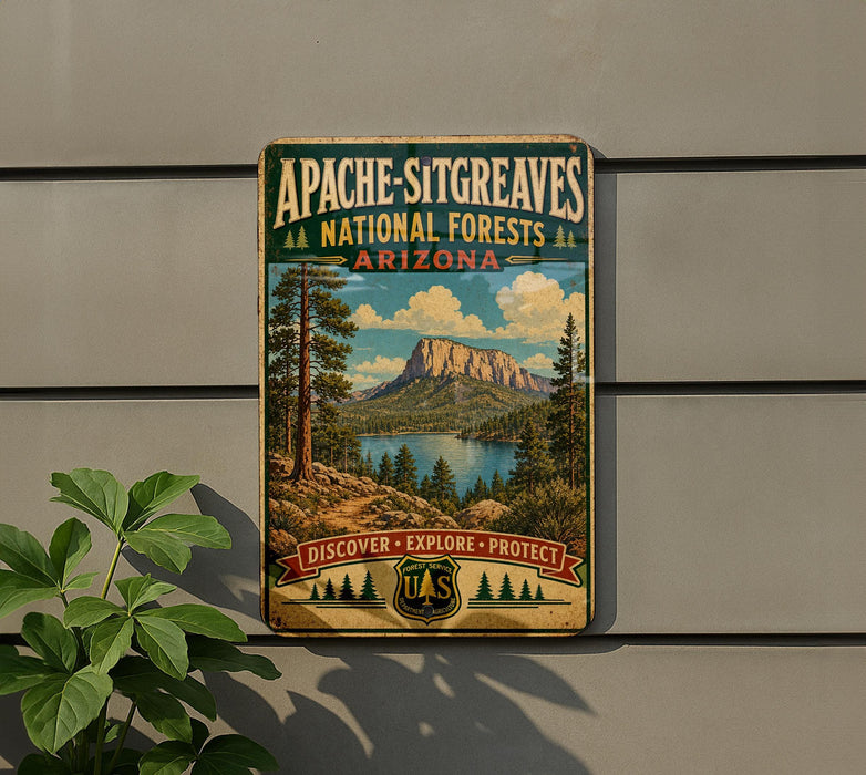 A vintage-style sign for Apache-Sitting Greaves National Forests in Arizona, featuring a scenic landscape with a mountain, lake, and pine trees.