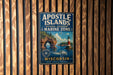 A vintage-style metal sign for the Apostle Islands National Lakeshore Marine Zone in Wisconsin, featuring a lighthouse and a scenic landscape.