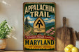 A vintage-style sign for the Appalachian Trail in Maryland, featuring a scenic mountain landscape and trail marker.
