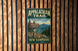 A vintage-style metal sign for the Appalachian Trail in New Hampshire, featuring a scenic mountain landscape and trail information.