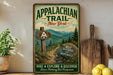 a vintage-style metal sign for the Appalachian Trail in New York, with a scenic mountain landscape and a wooden signpost. The sign also includes the text "Wild Beautiful and Meanwhile" and "Hike Explore Discover Leave Nothing But Footprints".